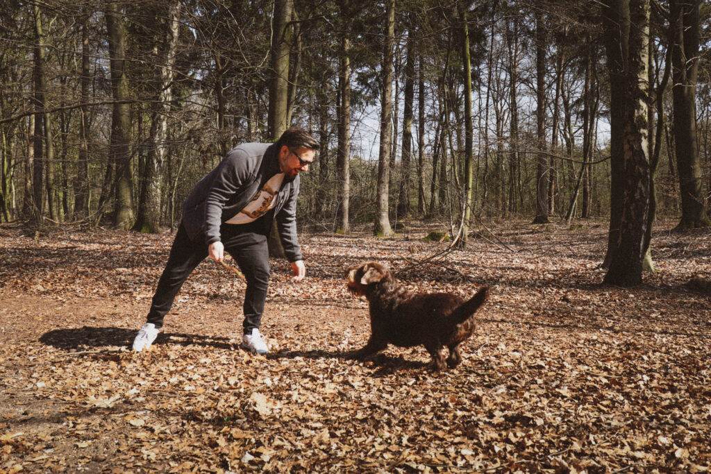 photo-of-a-man-playing-with-a-dog-in-a-dutch-forest