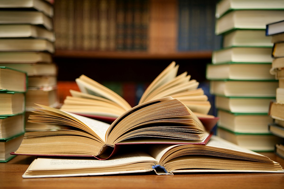 photo-of-open-face-book-amongst-a-pile-of-books