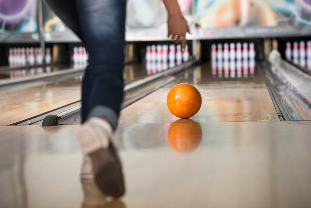 photo-of-person-bowling-throwing-an-orange-ball-towards-bowling-pins