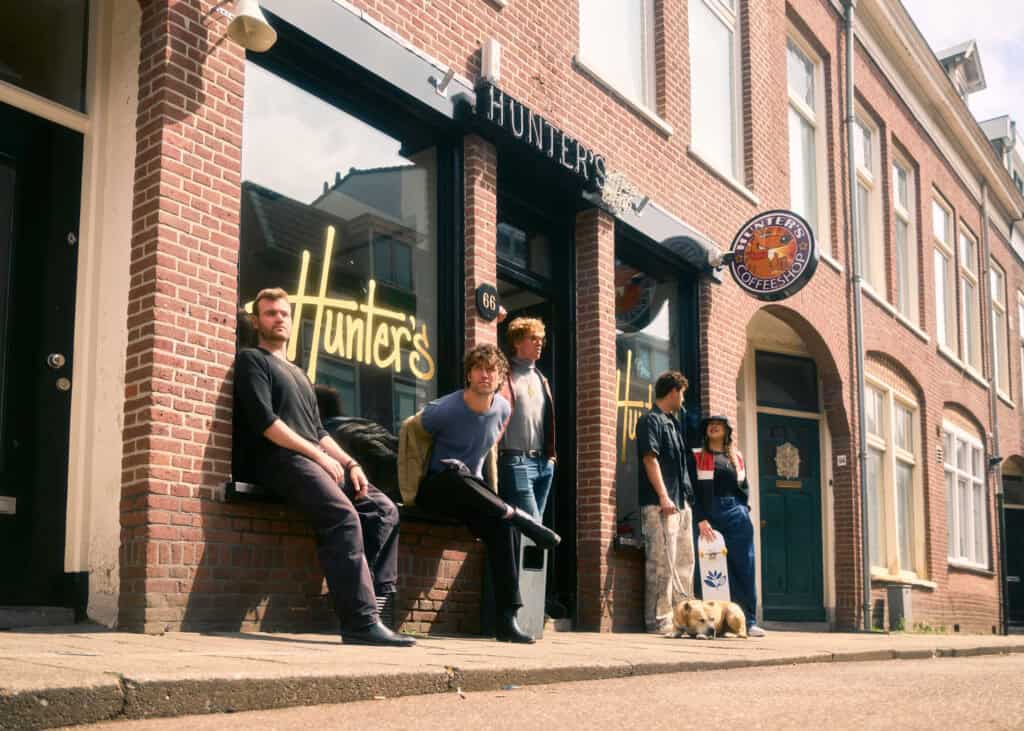 a group of young men standing in front of hunters coffeeshop in haarlem