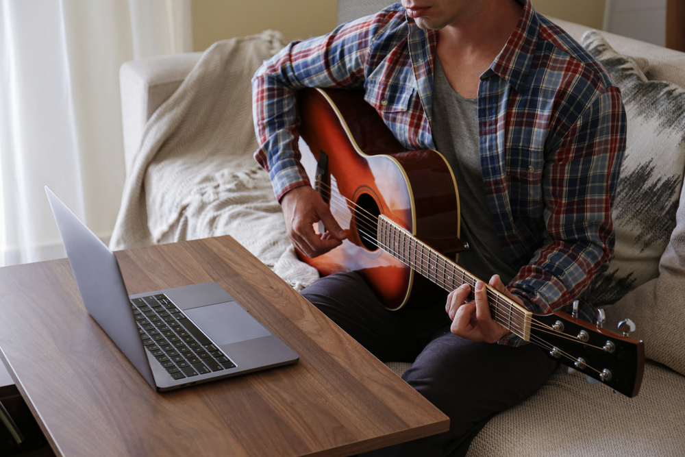 music-college-hipster-student-in-checkered-plaid-shirt-practicing-acoustic-guitar-exercise-reading-notes-from-laptop-computer