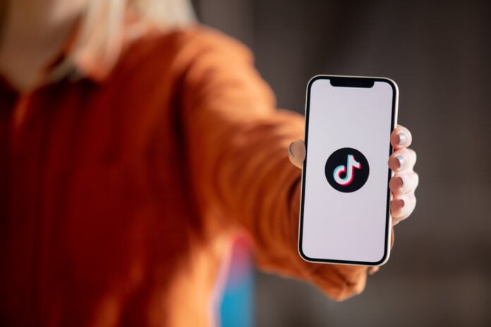 Photo-of-woman-holding-phone-with-Tik-tok-logo-on-screen