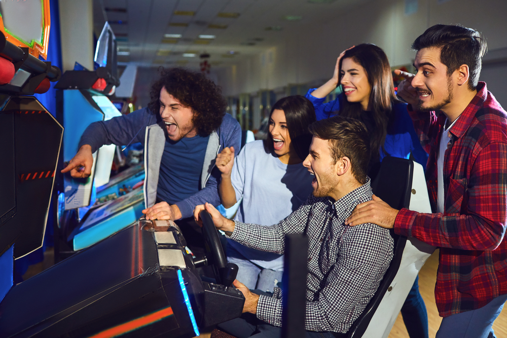 group-of–friends–playing–arcade-machine-in-an-amusement-park