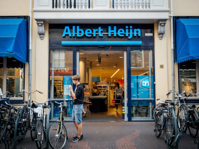 Young-man-standing-in-front-of-entrance-of-Dutch-supermarket-Albert-Heijn