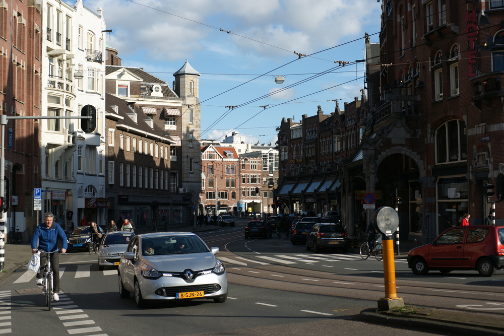 Photo-of-car-driving-in-the-city-with-beautiful-amsterdam-houses-surrounding-it