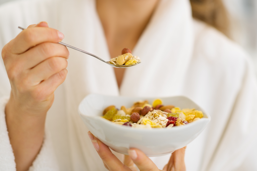 Close-up-of-woman-in-white-bathrobe-eating-a-bowl-of-muesli-at-sauna-in-the-netherlands