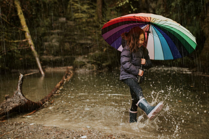 Child-playing-in-the-rain-with-an-umbrella-and-rain-boots