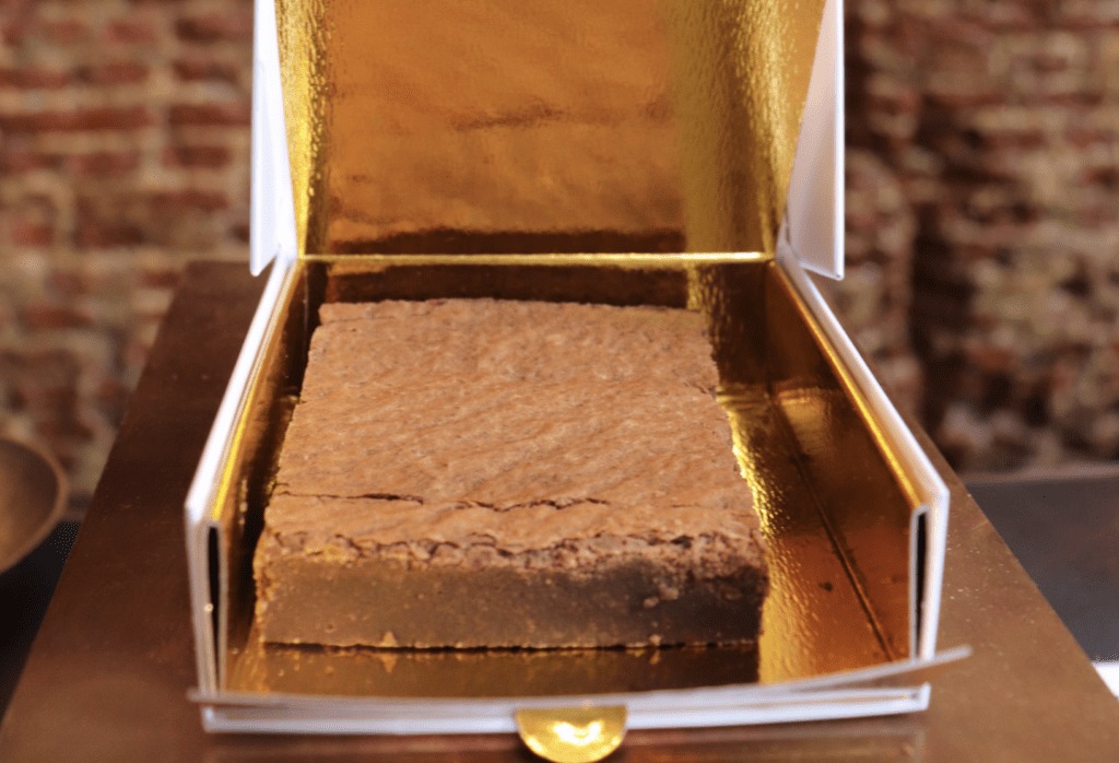 photo-of-famous-chocolate-brownie-edible-in-amsterdam-in-gold-box-with-brick-background