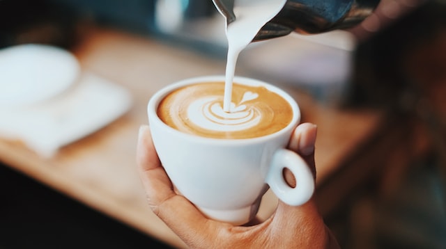 someone pouring latte art onto coffee