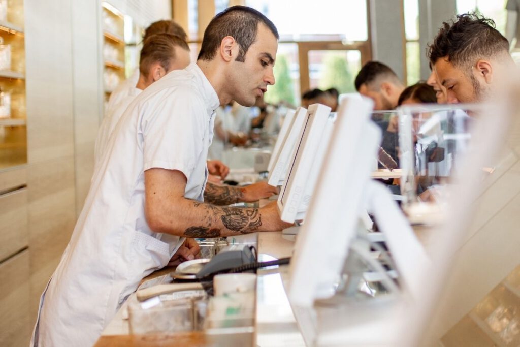 Budtender-at-coffeeshop-Boerejongens-wearing-white-apron-helping-customer-pick-weed-strain