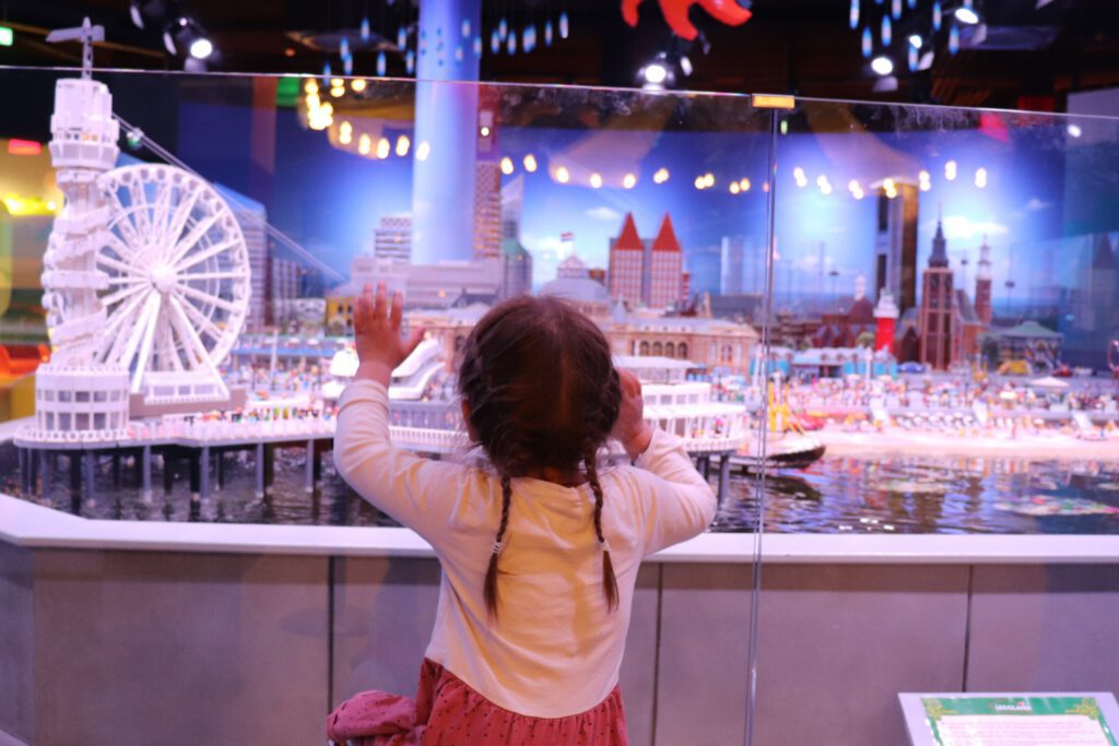 Girl-behind-glass-wall-of-The-Hague-LEGO-city-at-Scheveningen-LEGOLAND-Discovery-Centre