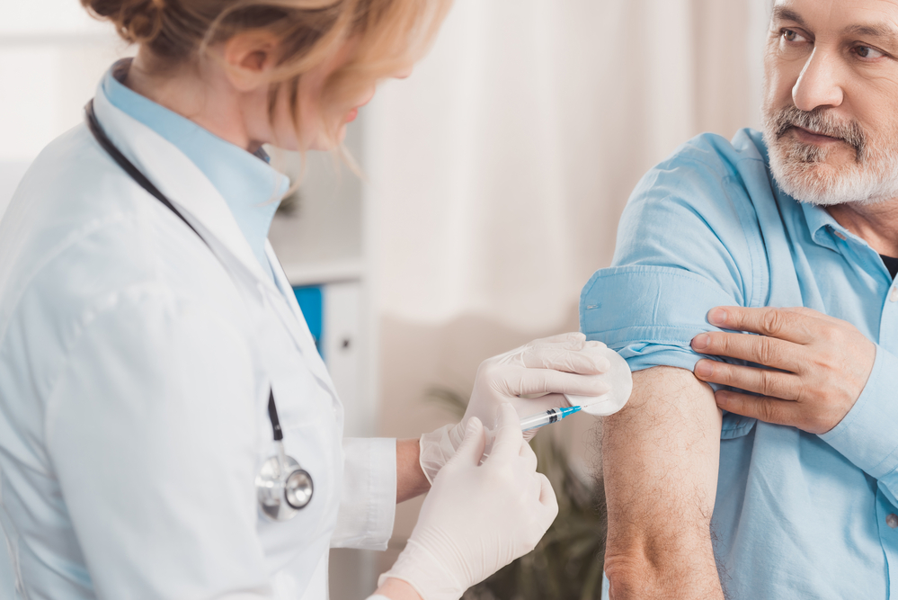 female-doctor-in-white-coat-giving-vaccination-to-elderly-man