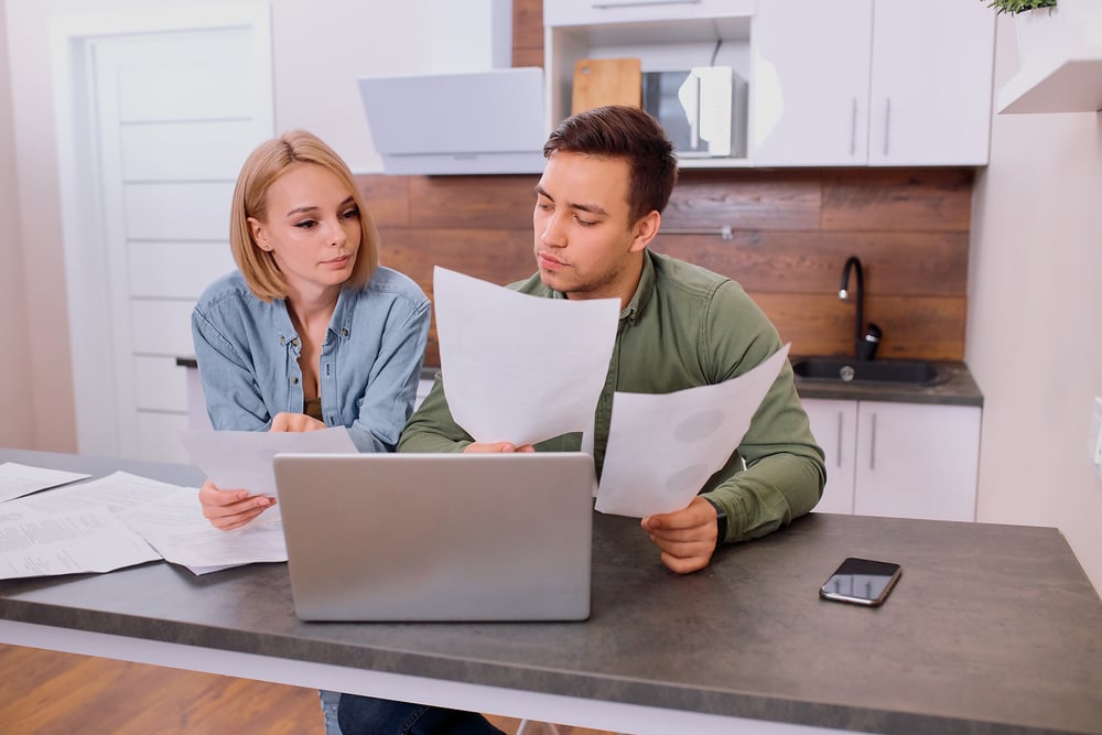 Photo-of-couple-at-desk-considering- paperwork-with-costs-of-buying-house-Netherlands