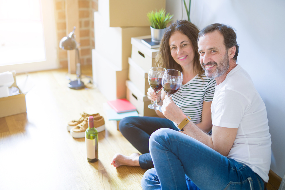 Photo-of-couple-celebrating-mortgage-on-floor-with-wine