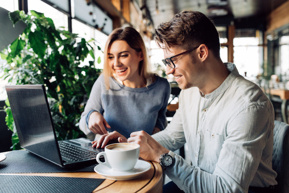 Photo-of-couple-discussing-data-while-sitting-at-laptop-in-cafe