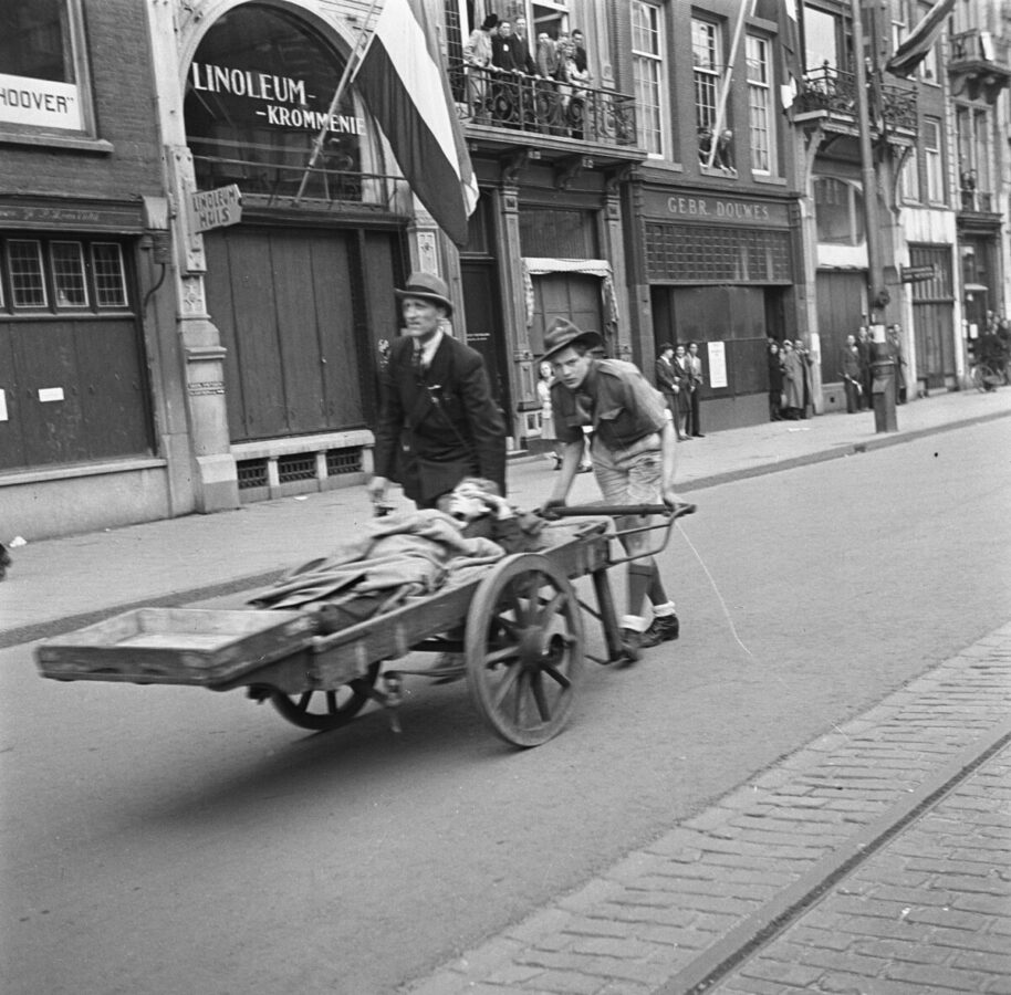 black-and-white-photograph-of-young-boy-pushing-injured-person-on-old-fashioned-war-stretcher