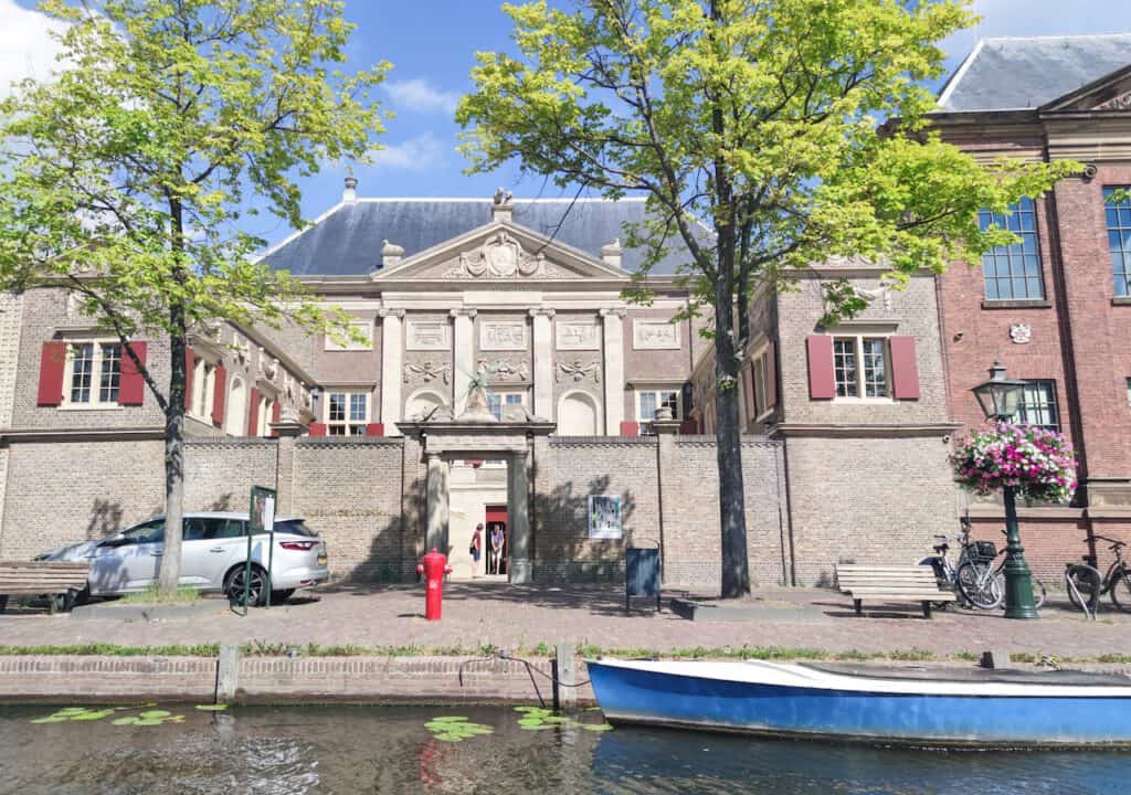 foto-de-lakenhal-exterior-em-Leiden-com-árvores-e-barco-em-um-canal