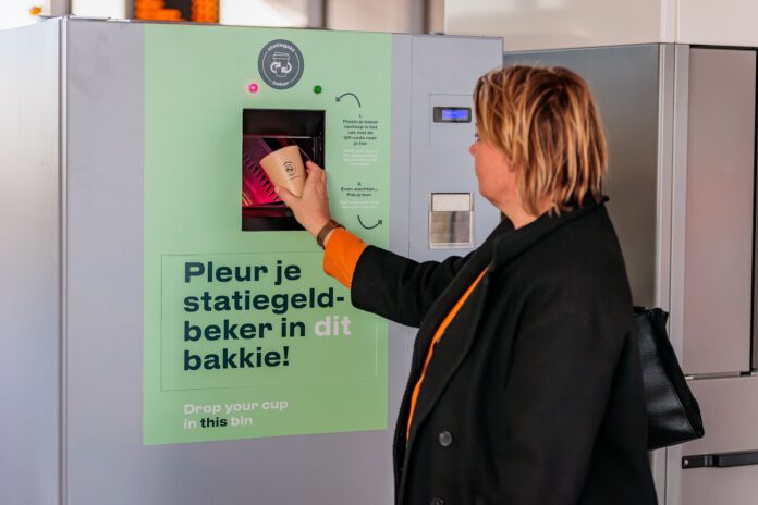 woman-depositing-reusable-coffee-cup-into-ns-machine