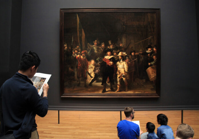 photo-visitors-admiring-rembrandt's-night-watch-at-the-rijksmuseum-in-amsterdam