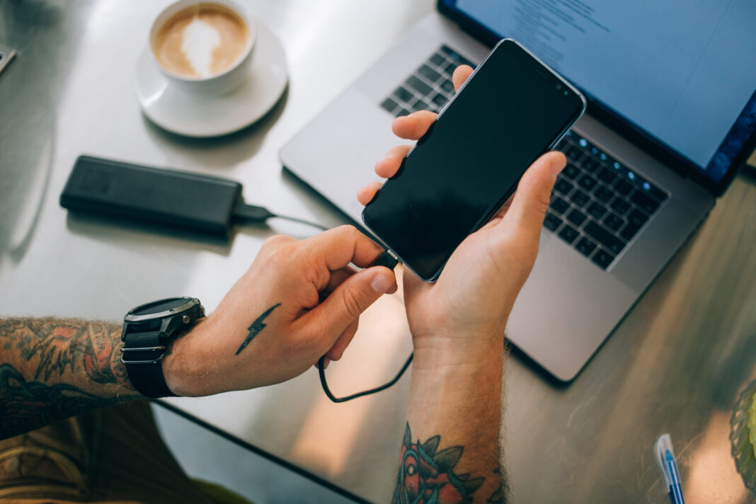 Photo of a person plugging their phone into a power bank.