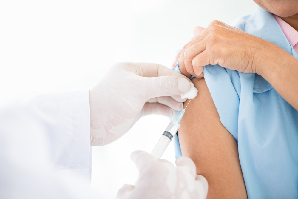 Dutch-patient-in-blue-hospital-gown-receiving-coronavirus-vaccine-from-doctor-with-white-gloves