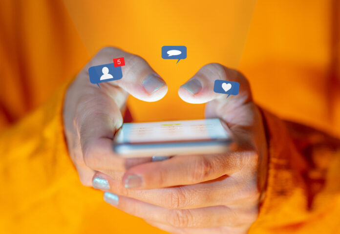 hands-of-a-woman-in-orange-sweater-receiving-notifications-on-phone