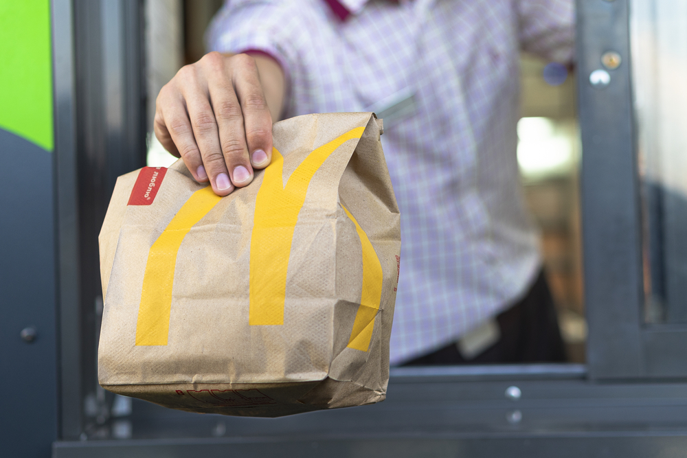 hand-holding-mcdonalds-takeaway-paper-bag-through-drive-through-window