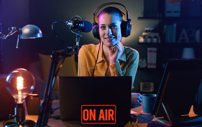 radio-show-hostess-smiling-behind-her-laptop-with-mic-and-headphones