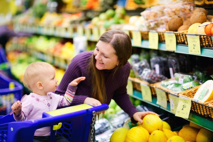 young-woman-with-a-child-buying-fruit-and-vegetables-at-the-supermarket