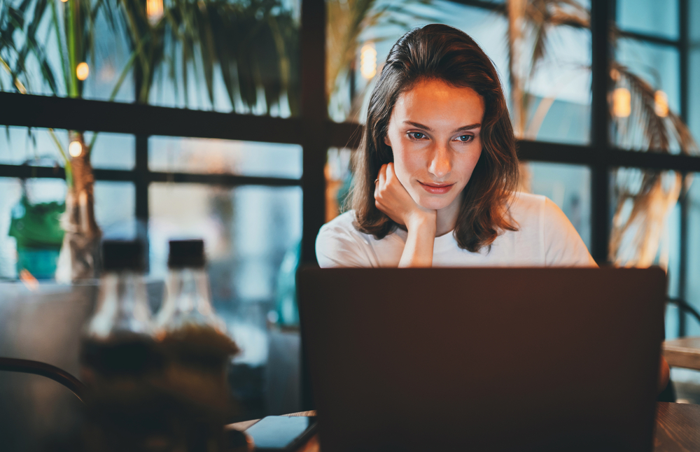 Photo-of-woman-sitting-at-desk-looking-at-laptop-using-Raisin-banking-online-savings-platform-in-Netherlands