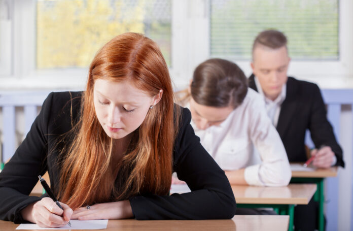 Photo of three people sitting an exam.