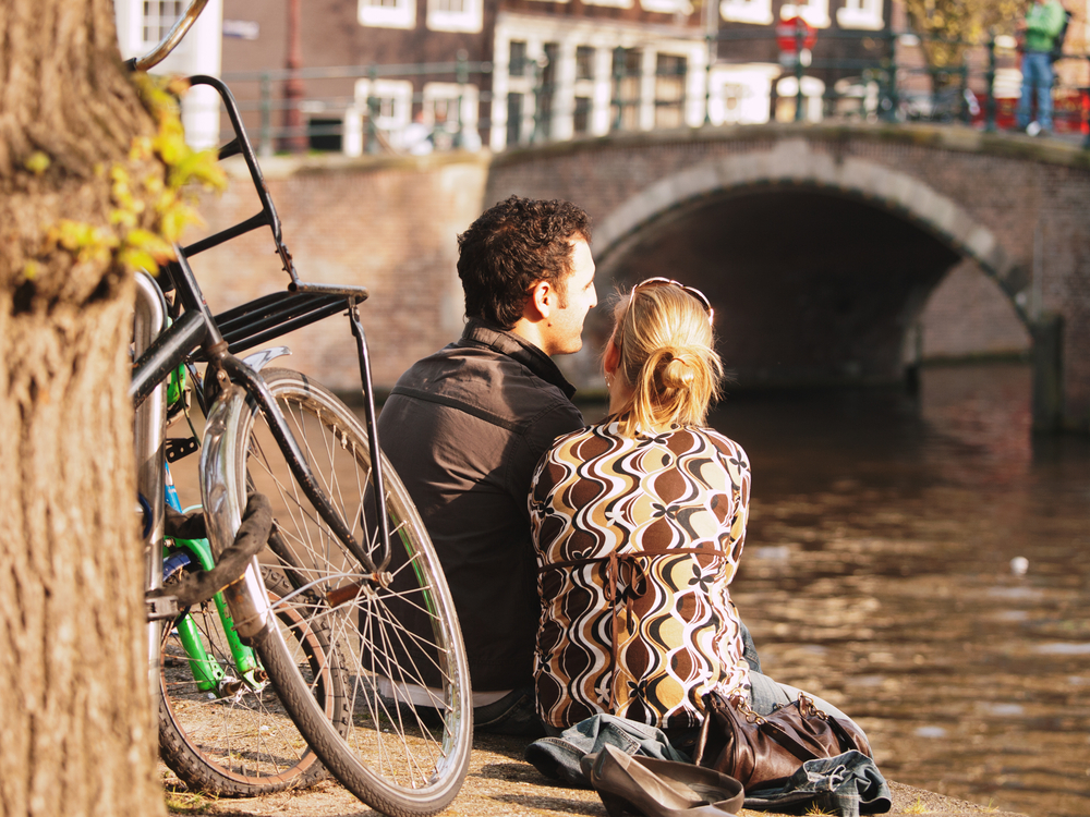 photo-of-a-couple-sitting-by-a-canal-enjoying-Amsterdam