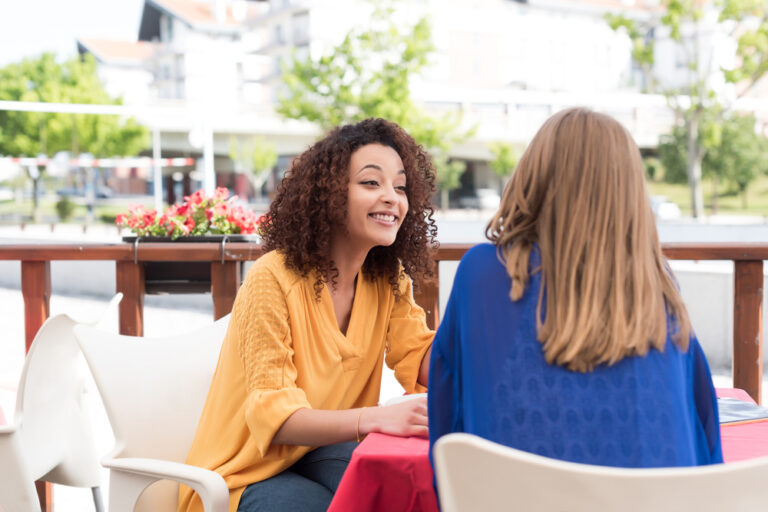 Photo-of-two-women-sitting-talking-Dutch-together-outside-friends-summer-day-cafe