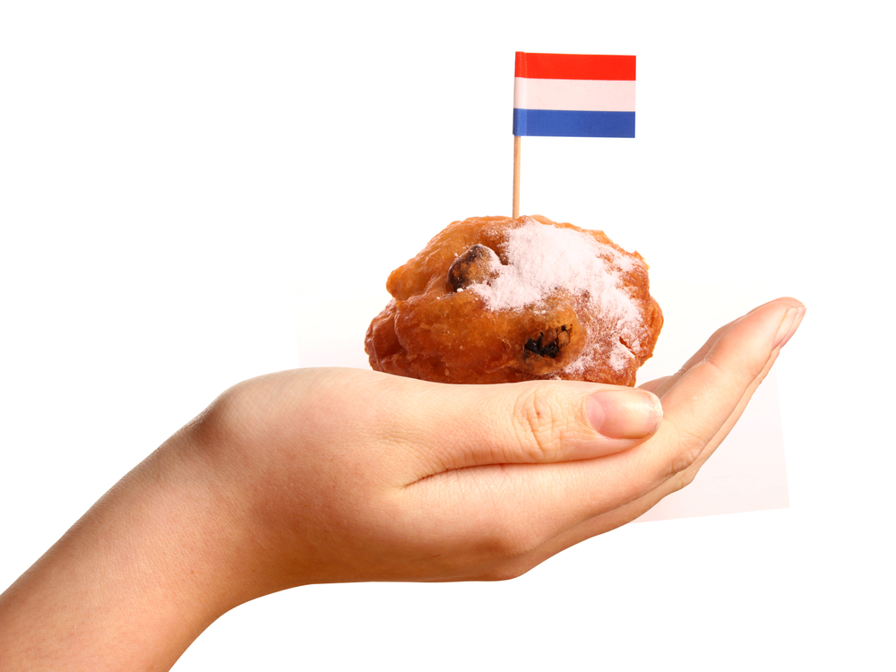 hand-holding-up-oliebollen-with-dutch-flag-on-top
