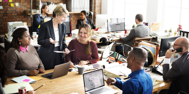 Group-of-diverse-employees-sitting-around-a-table-at-the-office-laughing