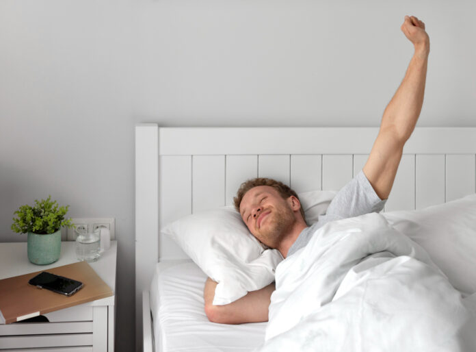 photo-of-man-stretching-in-bed-after-sleeping