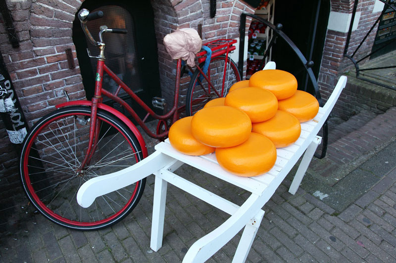 Dutch cheese on a cart for sale next to a bike.