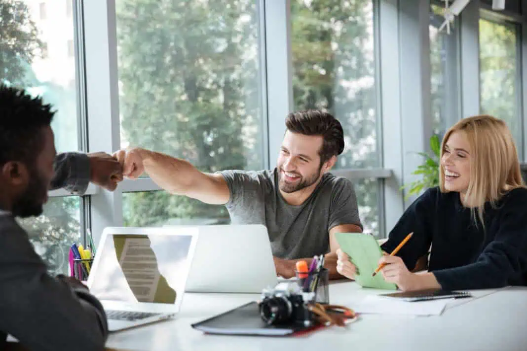 photo-of-Dutch-colleagues-sitting-around-desk-fist-bumping