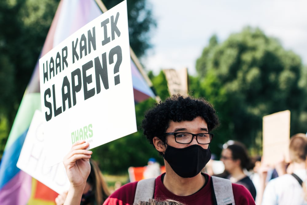 Young-man-holds-protest-sign-saying-where-can-i-sleep-in-dutch-to-protest-the-housing-crisis