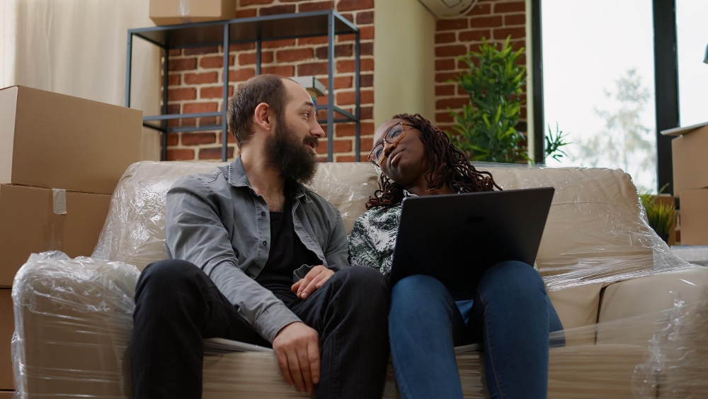 Photo-of-couple-sitting-on-couch-hoping-to-buy-house-in-the-Netherlands-while-Dutch-house-prices-are-lower