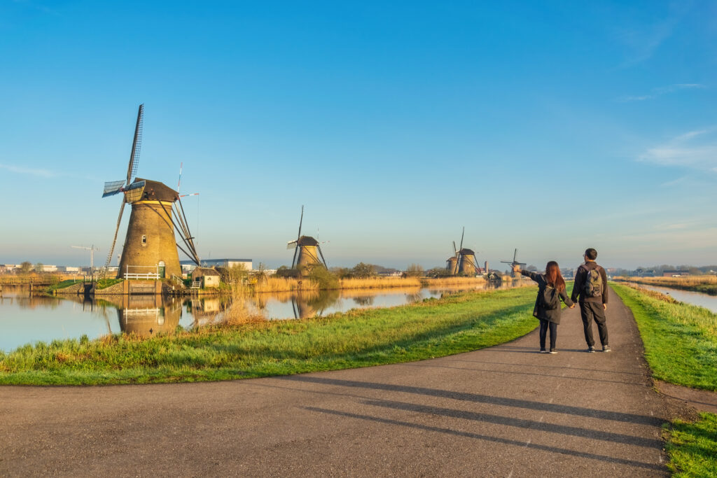 photo-of-man-and-woman-walking-near-Dutch-windmills-in-the-Netherlands