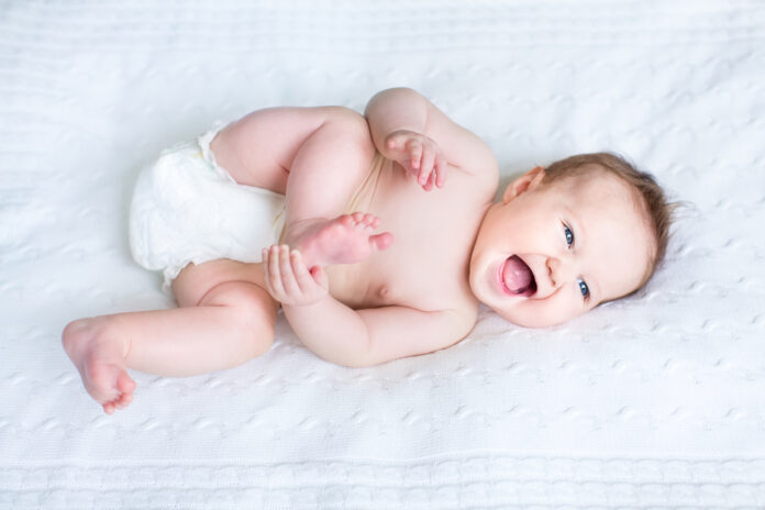 photo-of-cute-baby-smiling-on-white-sheets