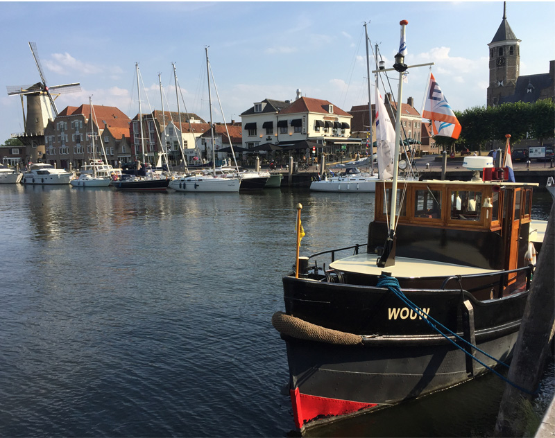 photo-of-Willemstad-harbour-on-a-sunny-day-with-boats-moored-and-windmill-in-distance-city-in-netherlands