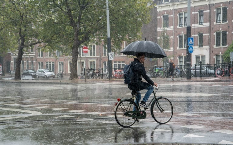 photo-of-man-biking-with-an-umbrella-in-the-netherlands
