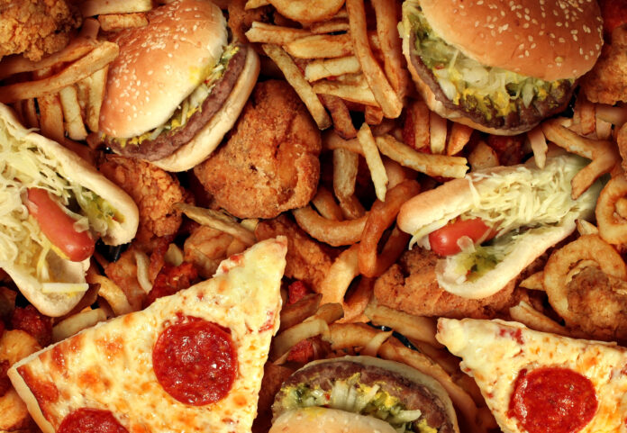 Photo of greasy looking fast food with slices of pizza, fries, and hamburgers.
