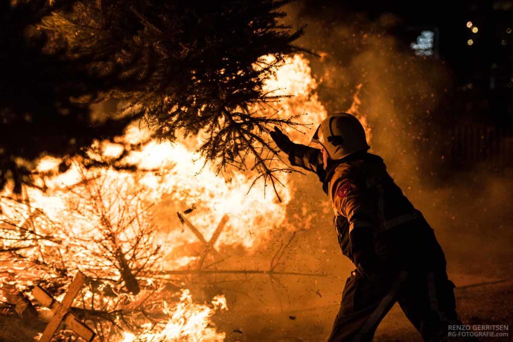 Man-throwing-a-christmas-tree-into-the-bonfire