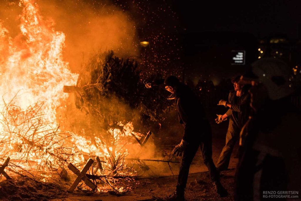 Three-men-throwing-a-christmas-tree-into-the-bonfire