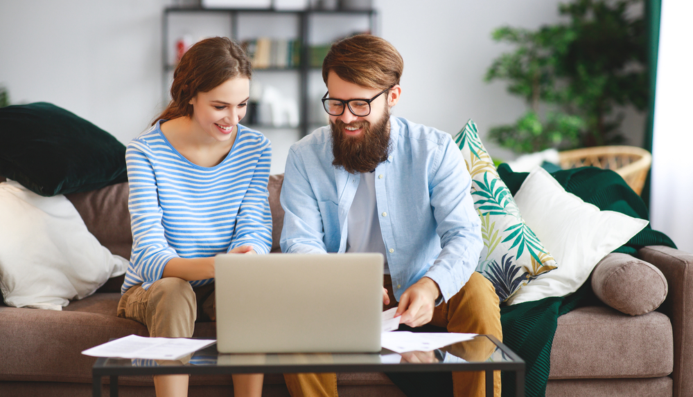 Photo-of-couple-looking-at-paperwork-and-laptop-smiling-after-buying-a-house-in-the-Netherlands