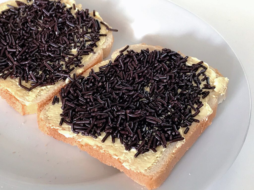 photo-of-two-slices-of-sandwich-bread-with-hageslag-dark-chocolate-butter-white-plate-white-bread-closeup