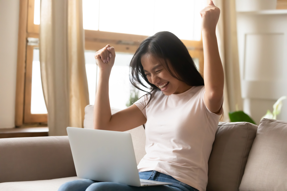 Happy-woman-looking-at-her-laptop-thinking-she-found-great-rental